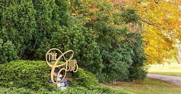 a sign in a grassy area with trees in the background