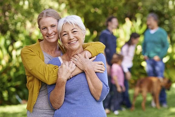 Two women hug each other in a park.