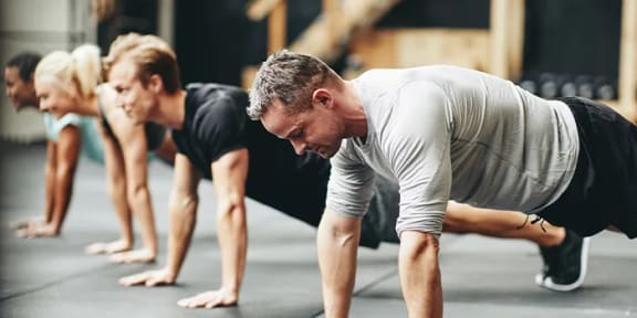 a group of people doing pushups in a gym