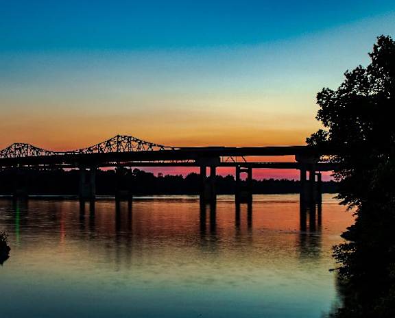 A bridge spans across a calm body of water at sunset.at The Robert Apartments, Alabama