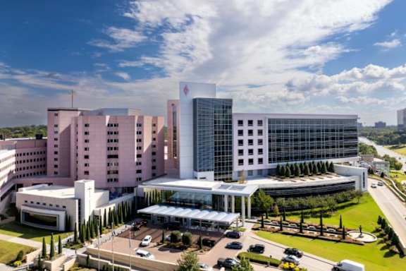 A large, modern building with a glass facade is the focal point of the image.