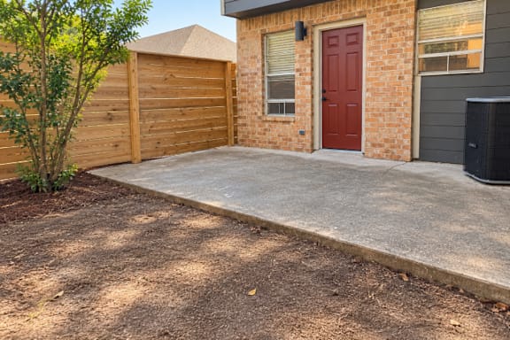 A red door is on the brick house.