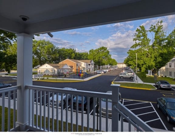 a view from a porch of a street with cars and houses