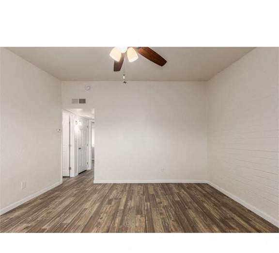 an empty living room with wood floors and a ceiling fan