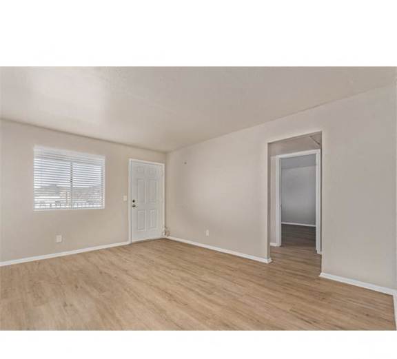 an empty living room with a door to a hallway