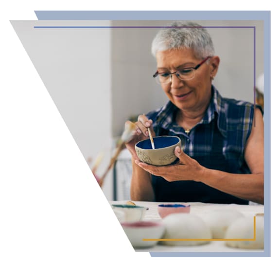 A woman is eating from a bowl with chopsticks.