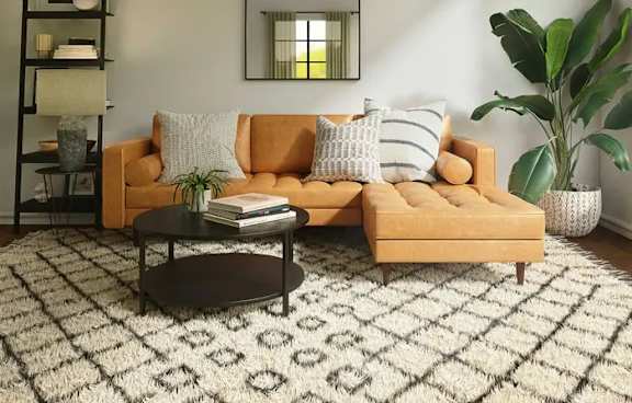 A living room with a yellow sofa, a black coffee table, and a large plant.