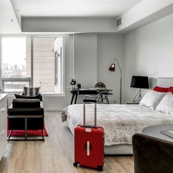 a bedroom with a bed and a red suitcase at Southpark on Whyte, Edmonton, Alberta