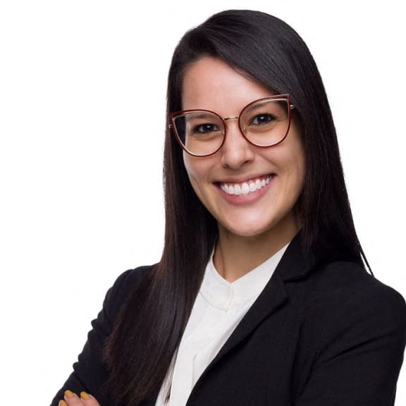a young woman wearing glasses and a suit and tie with her arms crossed