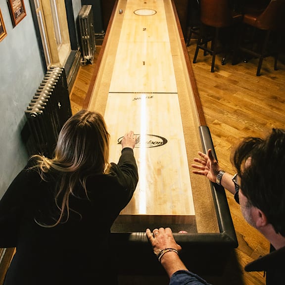 Two people playing a game on a long table.