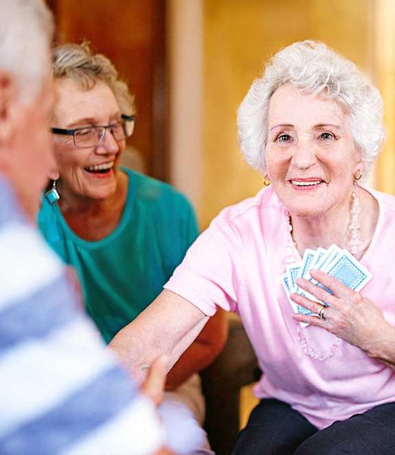 An elderly woman is holding a handful of blue cards.