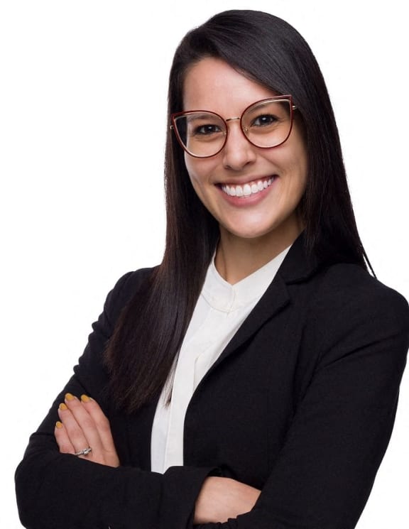 a young woman wearing glasses and a suit and tie with her arms crossed