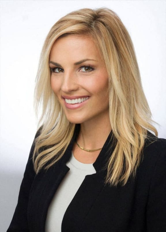 a woman with long blonde hair wearing a black jacket and a white shirt