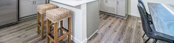 a kitchen with gray cabinets and a white counter top with three stools