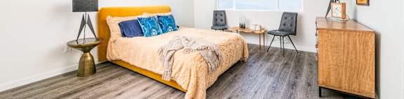 a bedroom with white walls and a yellow bed with blue and yellow pillows