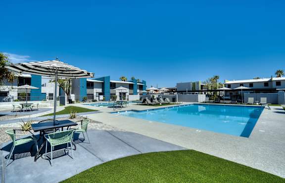 a swimming pool with tables and umbrellas at the clubhouse of a apartments complex at Connect on Missouri, Phoenix, 85015