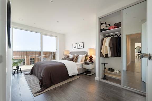 A bedroom with a large bed and a balcony.