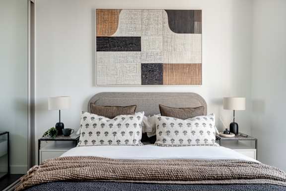 A bedroom with a large abstract painting above the bed.