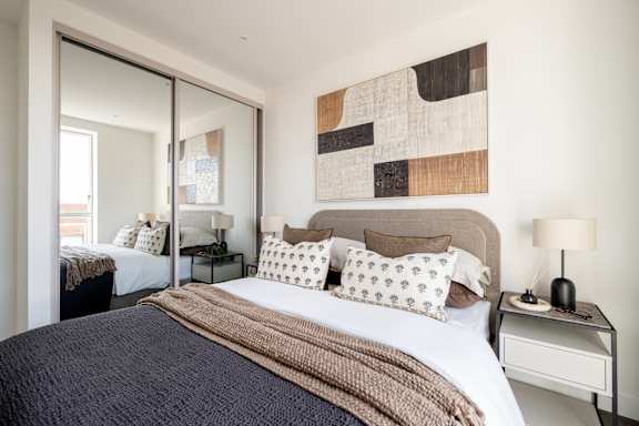 A bedroom with a large bed and a painting on the wall.