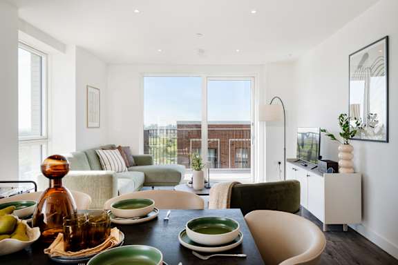 A dining table with green plates and a brown bottle on it.