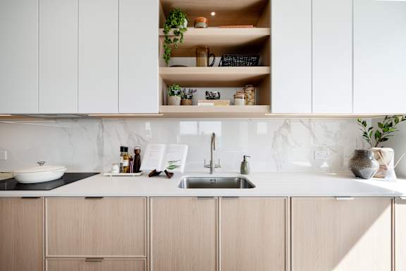 A kitchen with white cabinets and a marble backsplash.