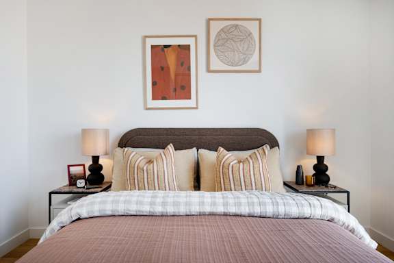 A bed with a striped pillow and a plaid comforter.
