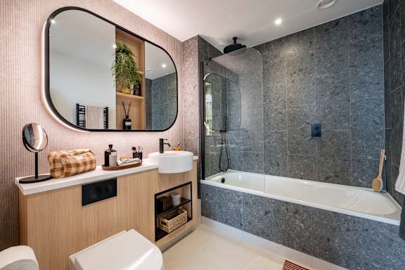 A bathroom with a round mirror, a white sink, and a white toilet.