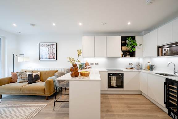 A modern kitchen with a yellow couch and a dining table.