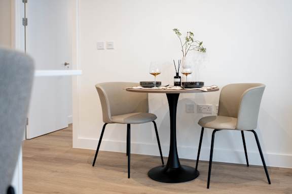 A black table with a glass of wine on it and two chairs.