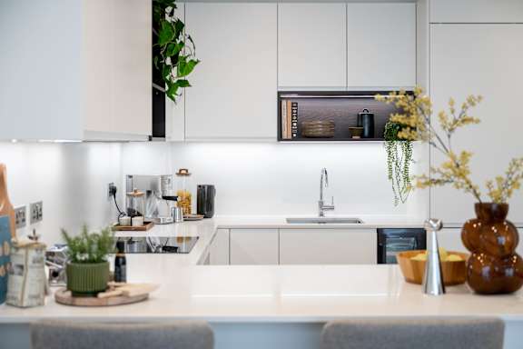 A modern kitchen with a white countertop and a grey chair.