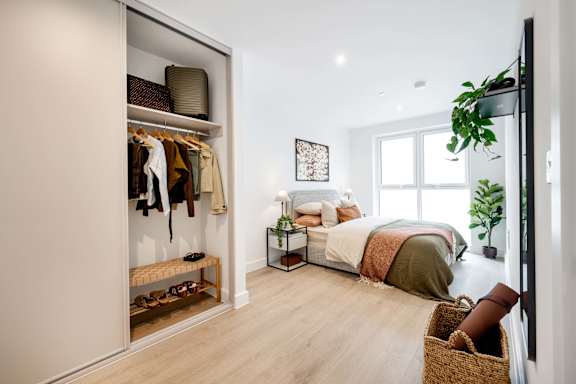 A bedroom with a bed, a wardrobe, and a potted plant.
