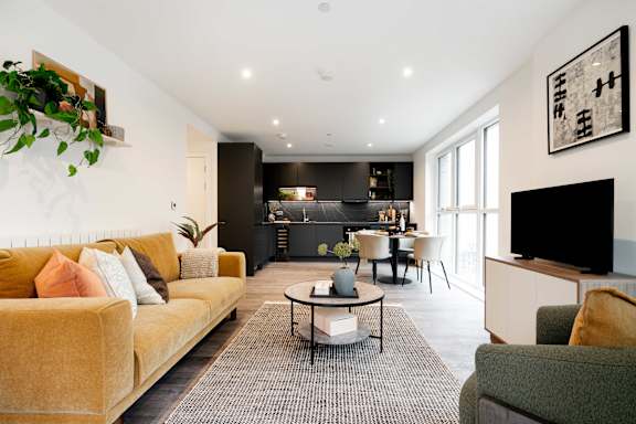 A living room with a yellow couch and a grey rug.