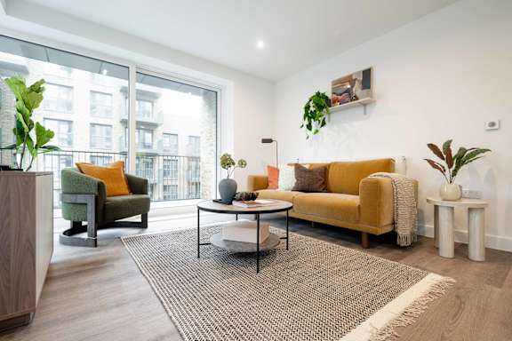 A living room with a yellow sofa, a green chair, and a wooden side table.