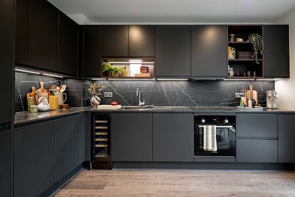 A modern kitchen with dark cabinets and a marble backsplash.