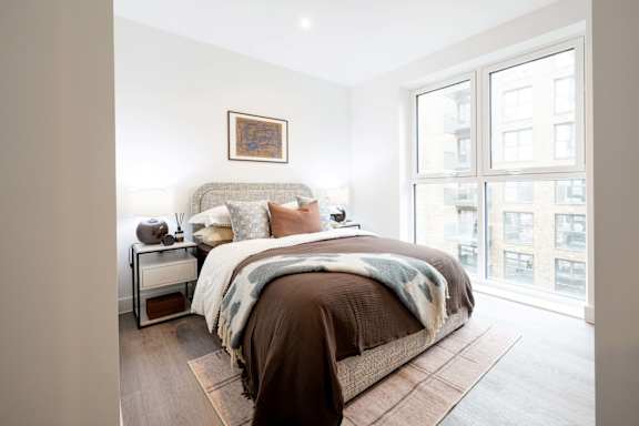 A bedroom with a large bed and a window overlooking a cityscape.