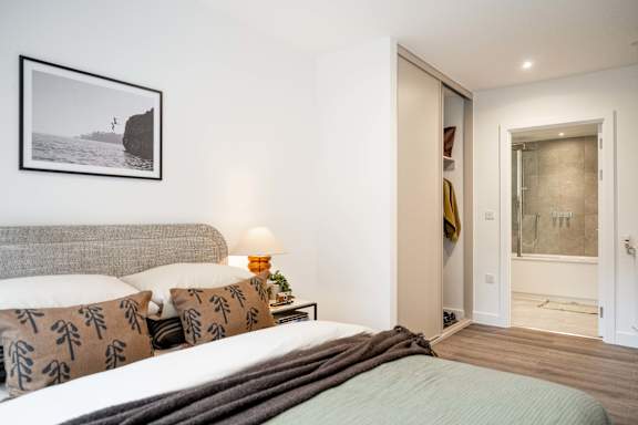 A bedroom with a bed, lamp, and picture on the wall.