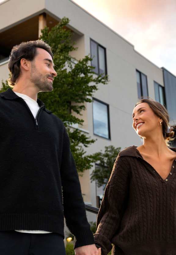 A man and a woman are walking hand in hand in front of a modern building.