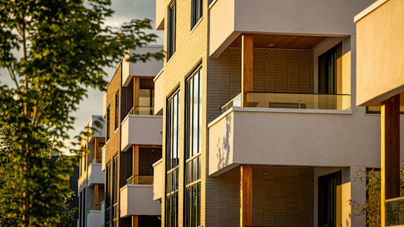 A modern apartment building with balconies and large windows.