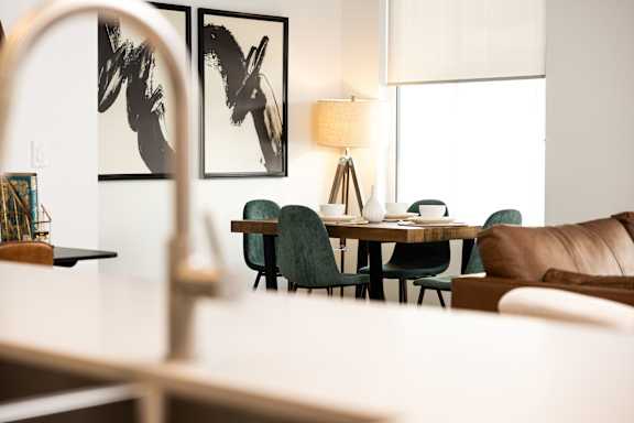 A living room with a white couch, a wooden table, and two abstract paintings on the wall.