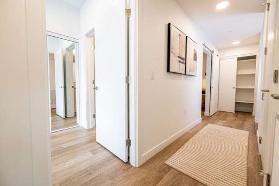 A hallway with a rug on the floor and a painting on the wall.