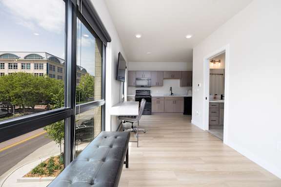 A modern kitchen with a black bench and a view of the street outside.