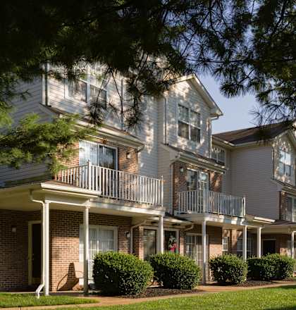 A row of houses with balconies and trees in front.