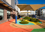 Thumbnail 7 of 7 - A playground with a colorful surface and a white canopy.