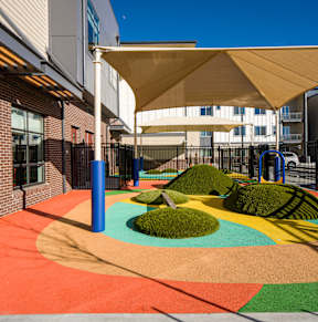 A playground with a colorful surface and a white canopy.