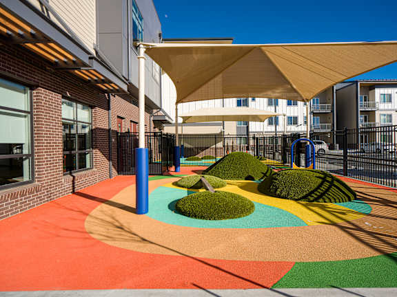 A playground with a colorful surface and a white canopy.
