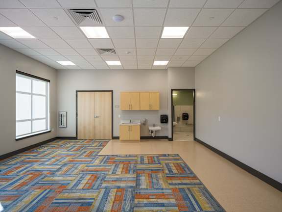 A room with a patterned carpet and a kitchenette.