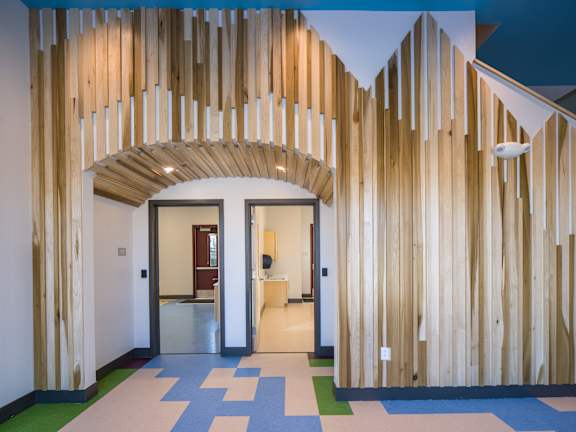 A hallway with a blue and white checkered floor and a wooden wall.