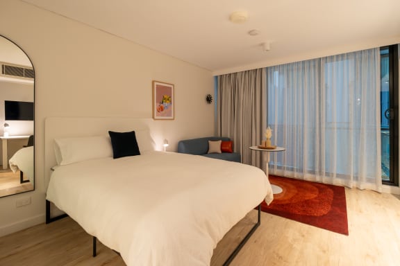 a large white bed in a room with a large window