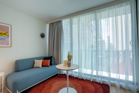 a living room with a blue couch and white curtains