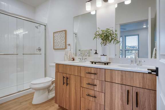 A bathroom with a toilet, sink, and mirror.